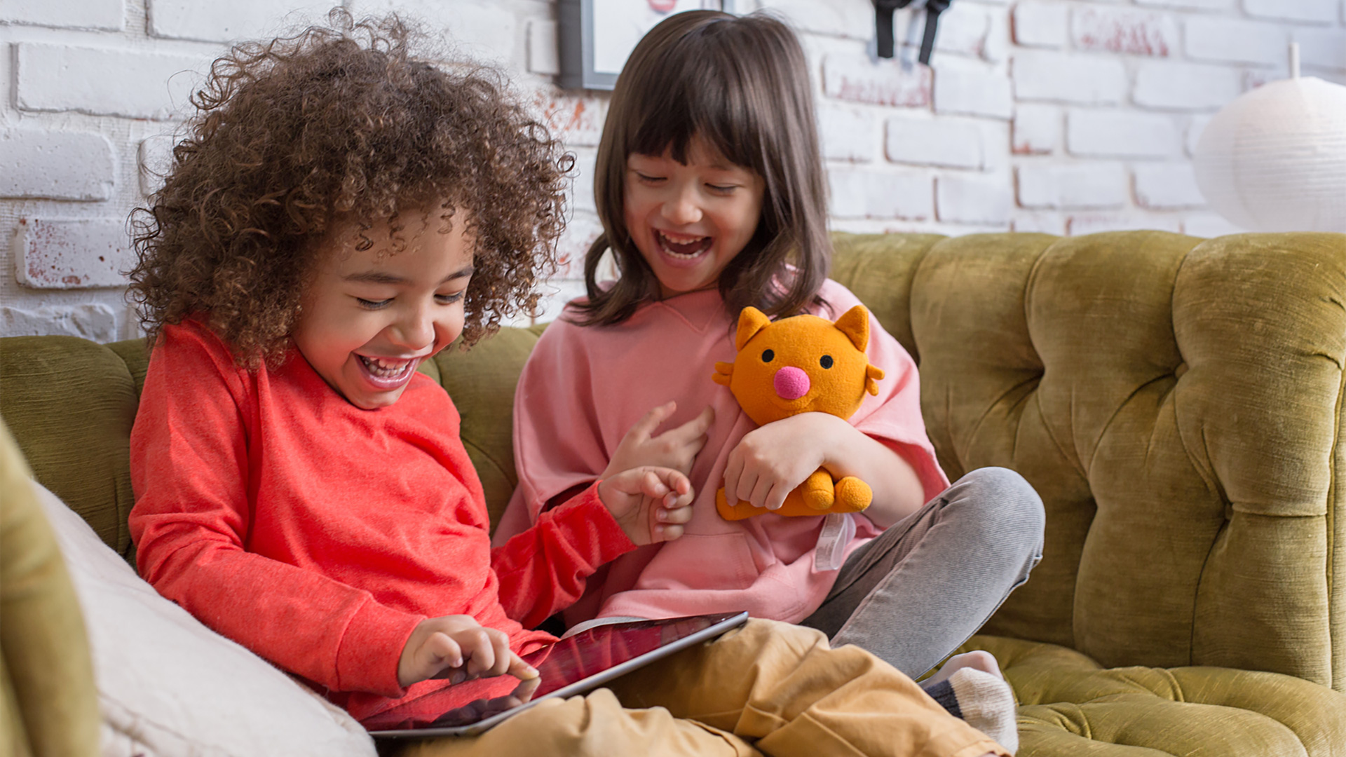 Two children smiling and playing with an iPad